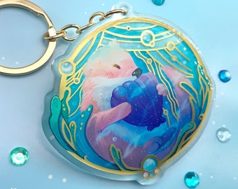 Sleutelhanger met afbeelding van een otter die een schelp vasthoudt in een frame met gouden details || origineel en schattig acryl bedeltje