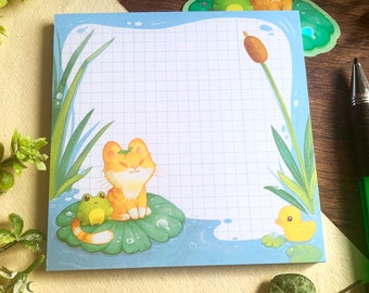 Bloc-notes  representant un petit chat sur un nénuphar accompagné de son ami grenouille - papier quadrillé , papeterie mignonne