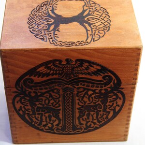 Peut inclure: Une bo&icirc;te en bois avec un motif de n&oelig;ud celtique sur le dessus et un motif d'arbre de vie sur le devant. La bo&icirc;te est en bois brun clair et a une teinture brun fonc&eacute;.