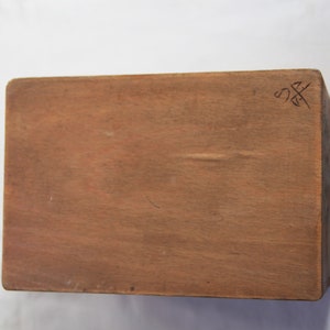 Peut inclure: Une bo&icirc;te en bois avec une finition brune. Le dessus de la bo&icirc;te porte une petite inscription qui dit "SS".
