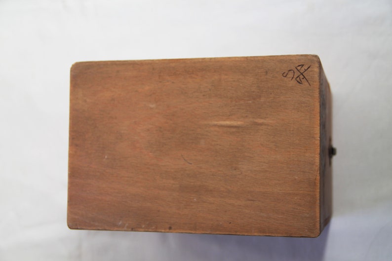 Peut inclure: Une bo&icirc;te en bois avec une finition brune. Le dessus de la bo&icirc;te porte une petite inscription qui dit "SS".