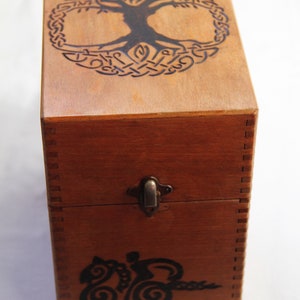 Peut inclure: Une bo&icirc;te en bois avec un motif de n&oelig;ud celtique sur le couvercle. La bo&icirc;te a un loquet et est en bois brun fonc&eacute;.