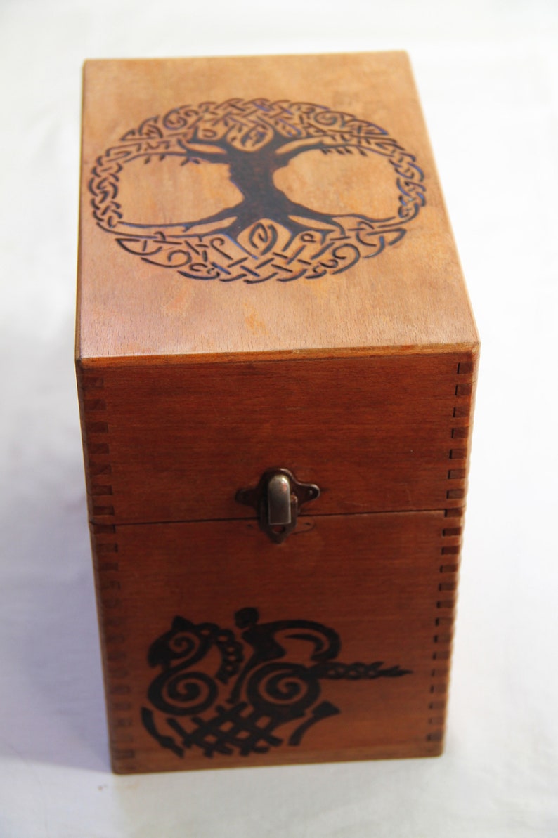 Peut inclure: Une bo&icirc;te en bois avec un motif de n&oelig;ud celtique sur le couvercle. La bo&icirc;te a un loquet et est en bois brun fonc&eacute;.