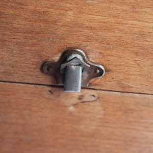 Peut inclure: Gros plan sur une bo&icirc;te en bois avec un loquet argent&eacute;. Le loquet est en forme d'&eacute;toile et poss&egrave;de une petite barre m&eacute;tallique qui coulisse dans une fente pour s&eacute;curiser la bo&icirc;te.