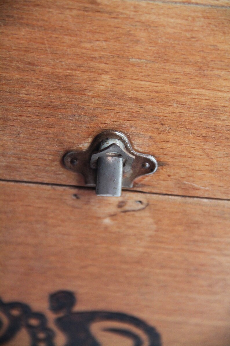 Peut inclure: Gros plan sur une bo&icirc;te en bois avec un loquet argent&eacute;. Le loquet est en forme d'&eacute;toile et poss&egrave;de une petite barre m&eacute;tallique qui coulisse dans une fente pour s&eacute;curiser la bo&icirc;te.