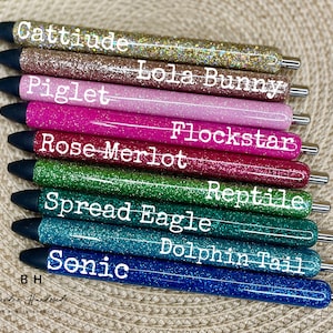 Puede incluir: Diez bol&iacute;grafos de purpurina con diferentes colores y nombres. Los nombres son: Cattitude, Lola Bunny, Piglet, Flockstar, Rose Merlot, Reptile, Spread Eagle, Dolphin Tail, Sonic y BH.