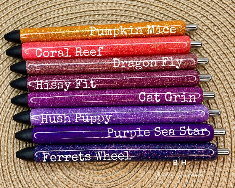 Puede incluir: Un conjunto de ocho bol&iacute;grafos con purpurina de diferentes colores y nombres impresos. Los nombres son: Pumpkin Mice, Coral Reef, Dragon Fly, Hissy Fit, Cat Grin, Hush Puppy, Purple Sea Star y Ferrets Wheel.