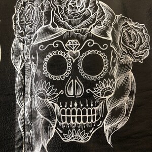 May include: White sugar skull with floral details on a black background. The skull has a diamond on its forehead and is surrounded by roses.
