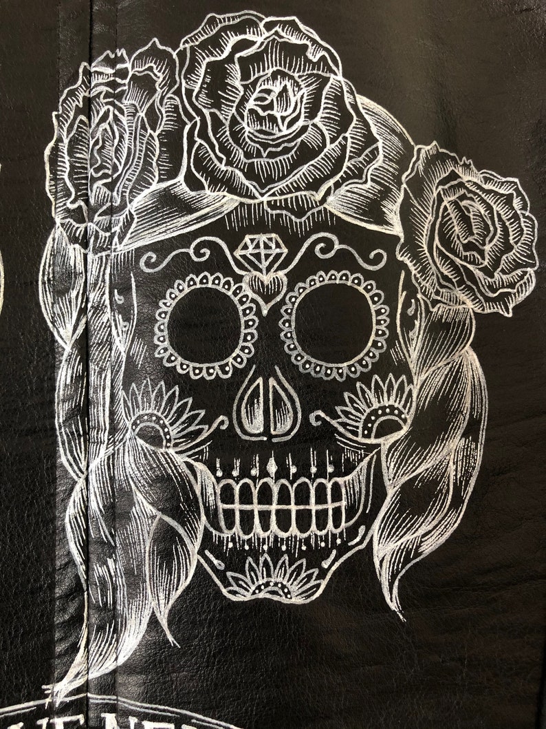 May include: White sugar skull with floral details on a black background. The skull has a diamond on its forehead and is surrounded by roses.