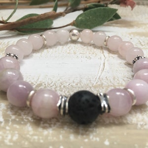 May include: A pink and white gemstone bracelet with a black lava bead and silver accents.