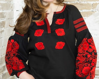 May include: A black embroidered blouse with red floral designs. The blouse has a V-neck and long sleeves.