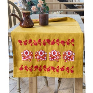 Mustard-colored table runner with a beautiful red and white floral embroidery