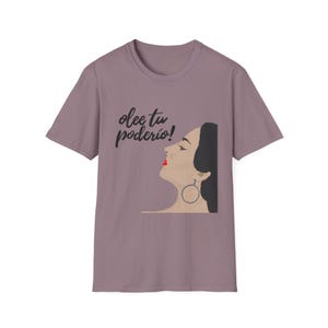 Puede incluir: Una camiseta color malva con una ilustración en blanco y negro de la cara de una mujer y el texto "olee tu poderio!"