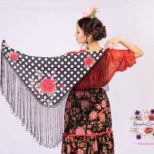 Könnte beinhalten: Ein schwarzer Schal mit Polka-Dots, floralem Design und langen Fransen. Der Schal ist Teil eines Flamenco-Outfits mit einem roten Blumenkleid und einem roten Spitzentop. Das Outfit ist für den traditionellen spanischen Tanz konzipiert.
