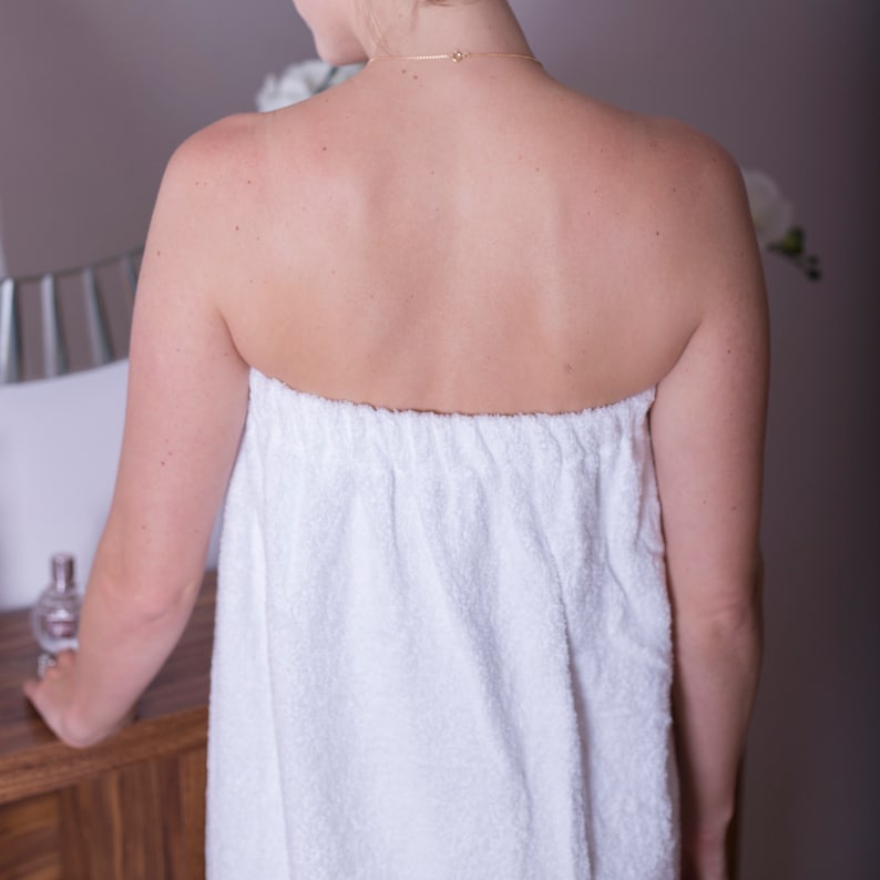 May include: White terry cloth wrap with a gathered elastic waistband. The wrap is worn by a person, but the person is not visible in the image.