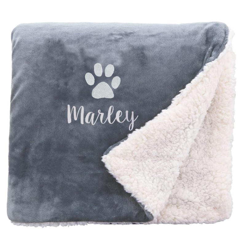 May include: Gray and white fleece blanket with a paw print and the name "Marley" embroidered on it.