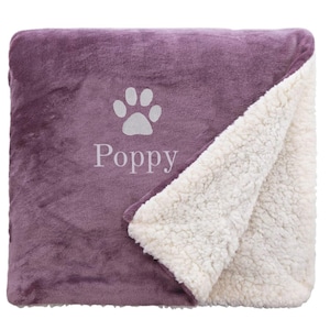 May include: Purple fleece pet blanket with a white paw print and the name "Poppy" embroidered on it. The blanket has a white sherpa lining.