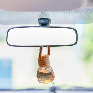 car diffuser in tiny glass jar hanging from rear view mirror filled with essential oils