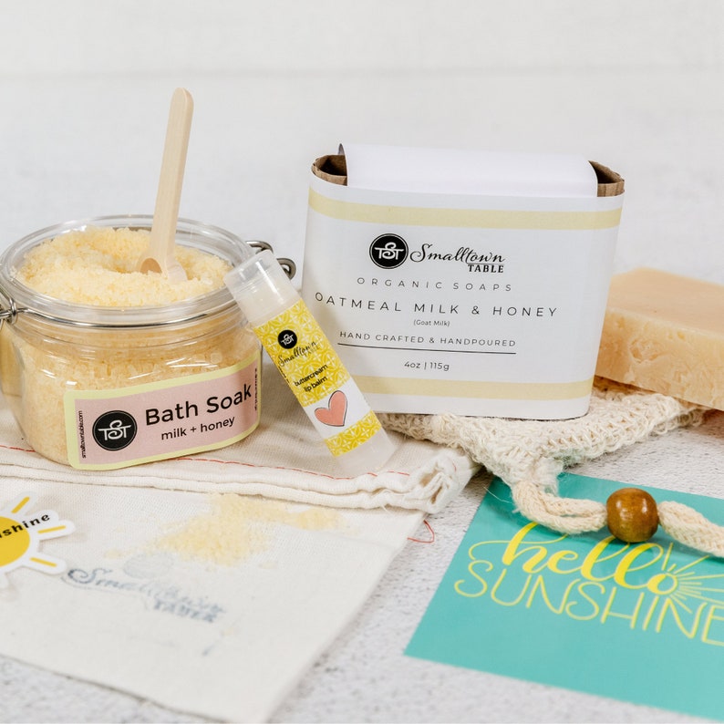 Our most popular scent honey oatmeal milk here shower is a large jar of bath salts, buttercream lip balm and soap bar. Pretty yellow colors and a turquoise card that says hello sunshine
