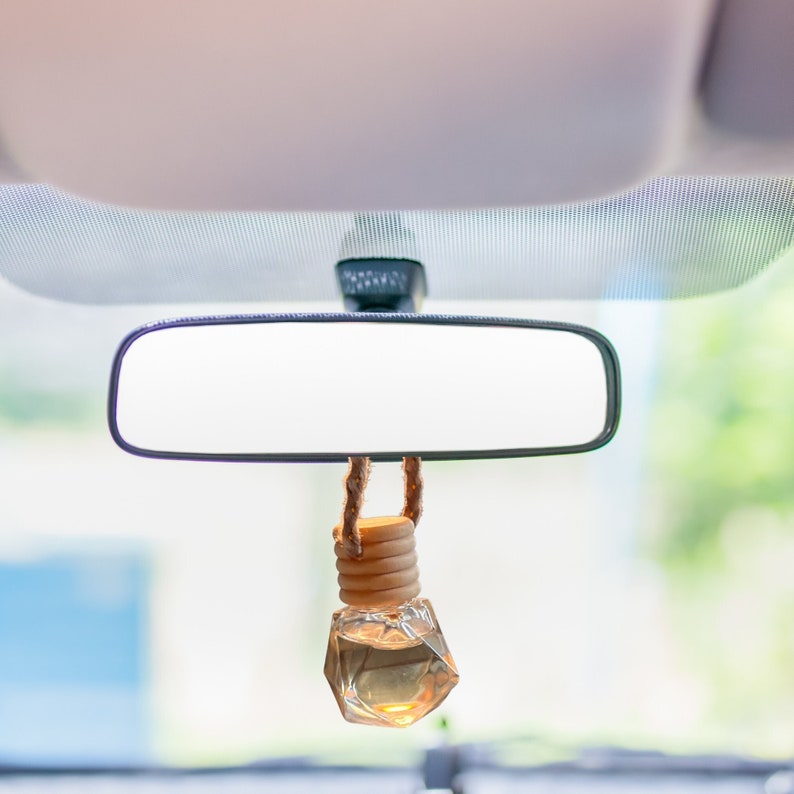 car diffuser in tiny glass jar hanging from rear view mirror filled with essential oils