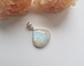 May include: A silver pendant with a large, iridescent, semi-circular moonstone. The stone displays a play of color, with flashes of blue and rainbow hues. The pendant has a simple, elegant design.