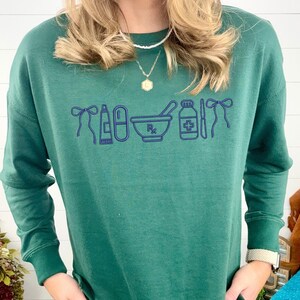 A person wearing a green sweater with a graphic design of medical supplies printed on it.