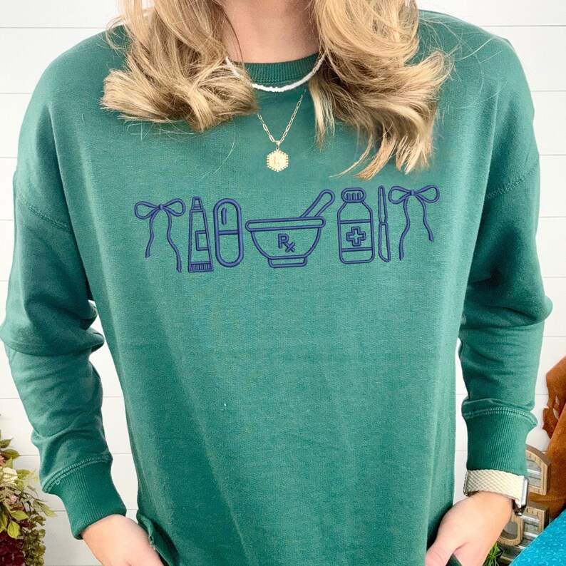 A person wearing a green sweater with a graphic design of medical supplies printed on it.