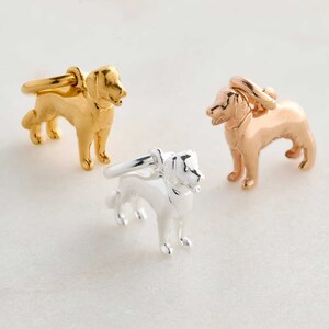 May include: Three dog-shaped rings in gold, rose gold, and silver. Each ring features a detailed canine figure with a ring band attached to the dog's back. The rings are displayed on a white surface.