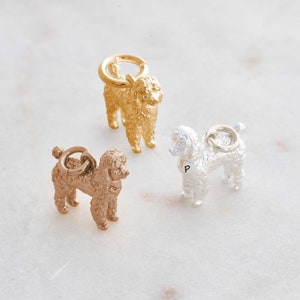May include: Three poodle dog charms in gold, rose gold, and silver. The charms are detailed and have a textured finish.