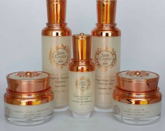 May include: A set of five skincare products in glass bottles and jars with gold lids. The products are labeled "Skin Candy" and include a cleanser, a serum, a mist, a treatment mask, and a night cream.