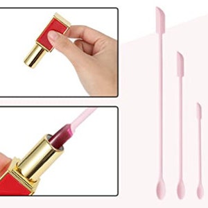Op de afbeelding: Drie roze siliconen lippenstiftapplicatoren in verschillende maten. De applicatoren hebben een puntige punt en een afgerond uiteinde. De applicatoren worden getoond naast een rode lippenstiftbuis met een gouden dop.
