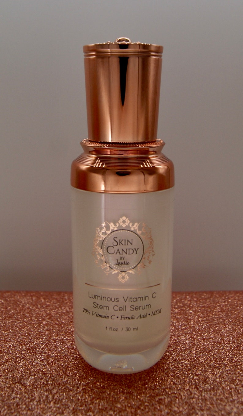 May include: A skincare product bottle with a copper-colored cap and base. The bottle is labeled "Skin Candy by Laurie" and contains "Luminous Vitamin C Stem Cell Serum." The bottle is 1 fl oz / 30 ml.
