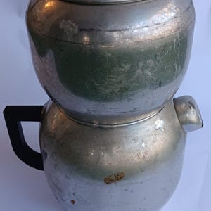 May include: A vintage silver aluminium coffee percolator with a black plastic handle and lid.