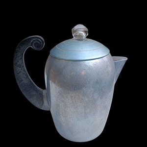以下が含まれることがあります： 淡い青色の蓋と透明なガラスのつまみが付いた、ヴィンテージの銀色のティーポット。 ハンドルは装飾的な渦巻き模様の濃いグレーです。 ティーポットには注ぎ口があり、黒い背景に配置されています。