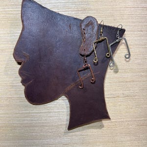 May include: Three pairs of musical note earrings made of wire. The earrings are in silver, gold, and copper.