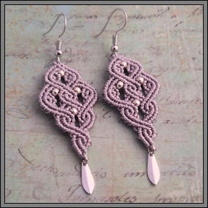 May include: A pair of purple and silver earrings with a knotted design and silver beads. The earrings have a teardrop-shaped pendant at the bottom.