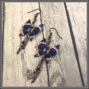 May include: A pair of blue and gold butterfly earrings with beaded dangles. The earrings are made with a macrame technique and have a bronze hook.