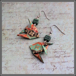 May include: A pair of origami earrings with green and gold patterned paper, green gemstone accents, and silver hooks.