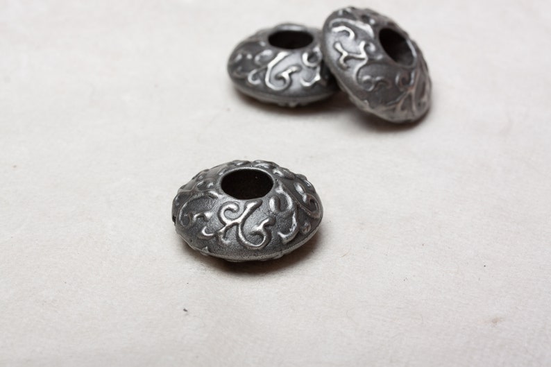 Puede incluir: Tres cuentas de metal plateado con un dise&ntilde;o floral decorativo. Las cuentas tienen un agujero en el centro y est&aacute;n dise&ntilde;adas para la elaboraci&oacute;n de joyas.