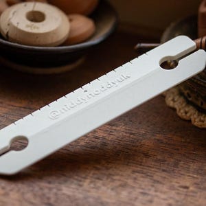 May include: White plastic tool with a handle and a ruler marked with the text "@middymoddyuk".