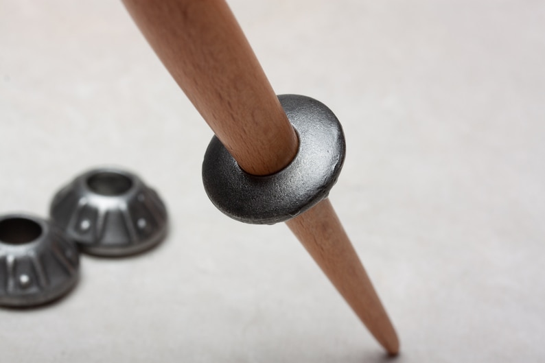 Op de afbeelding: Een houten tripodpoot met een metalen ring en twee metalen voeten. De ring is donkergrijs en de voeten zijn lichtgrijs.