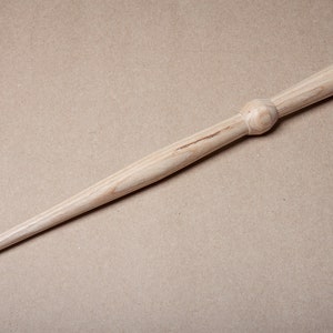 May include: A wooden dowel rod with a rounded knob on one end and a pointed tip on the other end.
