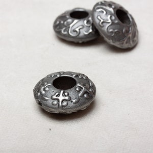 Puede incluir: Tres cuentas de metal plateado con un dise&ntilde;o decorativo. Las cuentas tienen un agujero en el centro y est&aacute;n dise&ntilde;adas para ser usadas como separadores o abalorios.