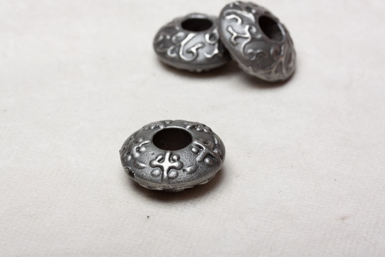 Puede incluir: Tres cuentas de metal plateado con un dise&ntilde;o decorativo. Las cuentas tienen un agujero en el centro y est&aacute;n dise&ntilde;adas para ser usadas como separadores o abalorios.