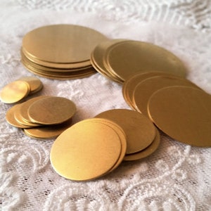 Può includere: Una collezione di cerchi metallici dorati di varie dimensioni. I cerchi sono disposti in pile e sparsi su una superficie di pizzo bianco. Il metallo ha una finitura opaca.