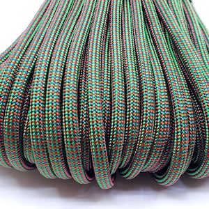 May include: Close-up of a bundle of green, red, and black paracord. The paracord has a woven pattern.