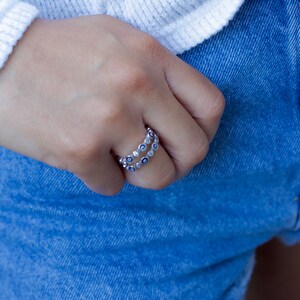 May include: A silver ring with a double row of blue and white evil eye charms.
