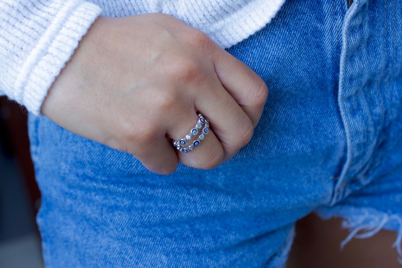 May include: A silver ring with a double row of blue and white evil eye charms.