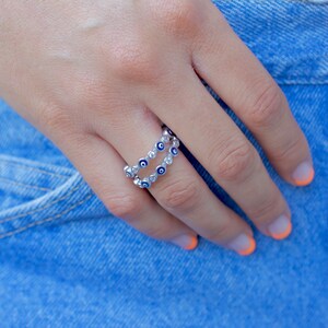 May include: A silver ring with a double row of blue and white evil eye charms.