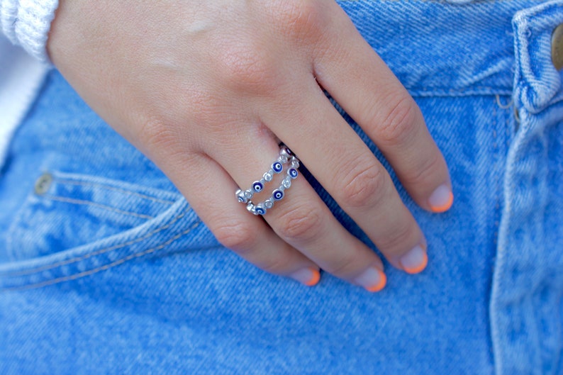 May include: A silver ring with a double row of blue and white evil eye charms.